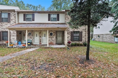 Traditional home featuring covered porch, brick siding, and a front yard