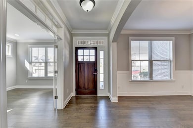 Foyer with dark wood-style flooring, arched walkways, and a healthy amount of sunlight