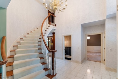 Stairway featuring tile patterned floors, a towering ceiling, a chandelier, and wallpapered walls