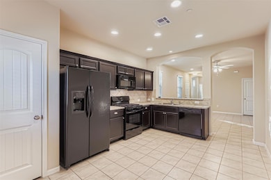 Kitchen with black appliances, tasteful backsplash, light tile patterned flooring, arched walkways, and a ceiling fan