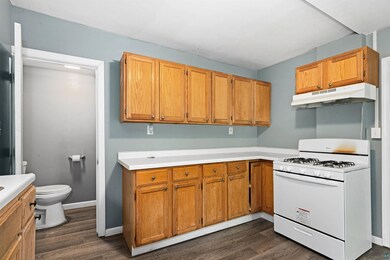 Kitchen with gas range gas stove, under cabinet range hood, dark wood-type flooring, and light countertops