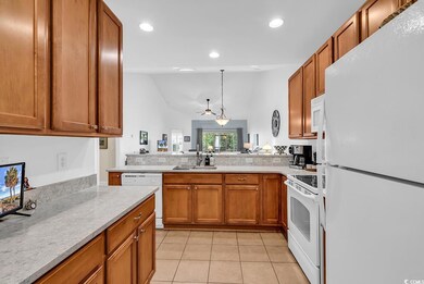 Kitchen featuring white appliances, light tile patterned floors, light countertops, a peninsula, and brown cabinets