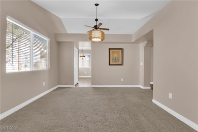 Carpeted empty room featuring a ceiling fan, vault