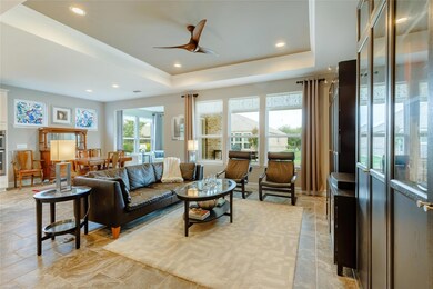 Living room with a tray ceiling, ceiling fan, and 