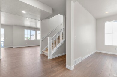 Unfurnished room with stairs, light wood finished floors, recessed lighting, and a textured ceiling