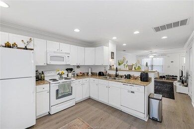 Kitchen with white appliances, a peninsula, light