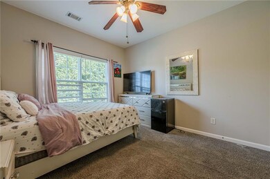 Carpeted bedroom featuring black fridge and a ceiling fan