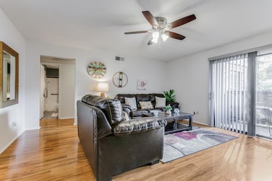 Living room with ceiling fan and light wood-type f