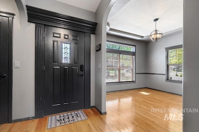 Foyer featuring healthy amount of natural light, light wood-style floors, a chandelier, and a textured ceiling