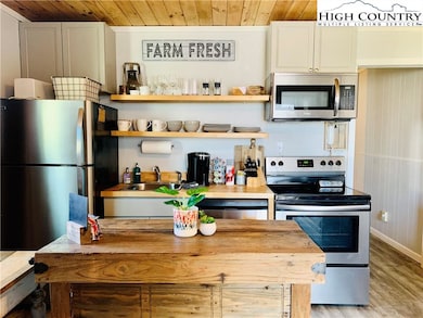 New kitchen with stainless appliances and wood cei