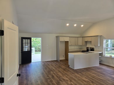 Kitchen featuring a peninsula, dark wood-style flooring, recessed lighting, light countertops, and high vaulted ceiling