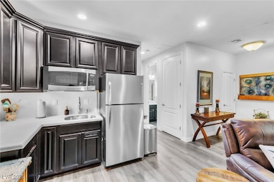 Kitchen with appliances with stainless steel finishes, light wood-style flooring, recessed lighting, and light stone countertops