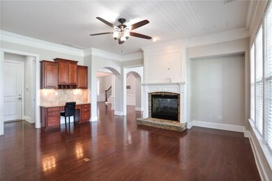 Unfurnished living room with built in desk, dark wood finished floors, a wealth of natural light, and ceiling fan