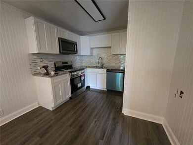 Kitchen featuring sink, dark hardwood / wood-style flooring, stainless steel appliances, and white cabinets