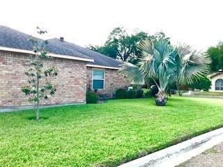 View of property exterior featuring brick siding and a lawn