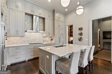 Kitchen featuring dark wood-style floors, backsplash, wall chimney range hood, a breakfast bar, and recessed lighting