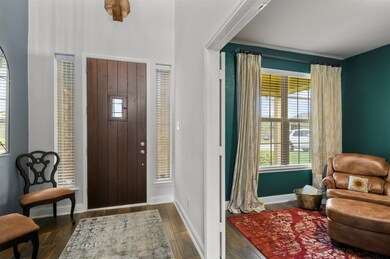 A view of the entryway and the solid wood front door with iron accented window that can be opened to greet guests or accept deliveries. A video doorbell enhances safety and allows you to monitor the home from anywhere. From this vantage point you can see into the study. This dedicated work space has French doors that can be closed when peace and quiet are needed to complete work tasks.