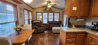 Kitchen with ceiling fan, dark wood-style flooring, crown molding, and lofted ceiling