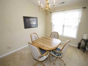 Dining room with a chandelier, baseboards, and carpet floors