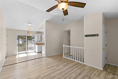 Unfurnished living room featuring light wood finished floors, a ceiling fan, vaulted ceiling, and a textured ceiling