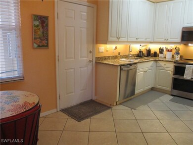 Kitchen featuring white cabinetry, stainless steel appliances, sink, light stone counters, and light tile patterned flooring
