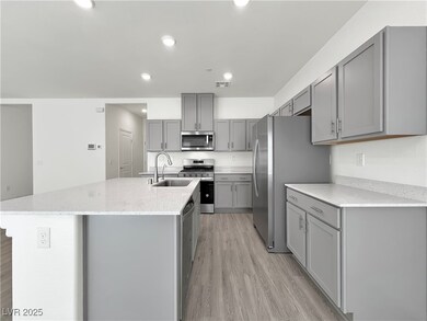 Kitchen featuring an island with sink, a sink, gra