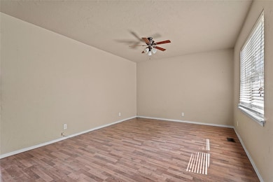 Empty room featuring wood finished floors, ceiling fan, and a textured ceiling