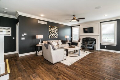 Family room with crown molding, can lighting, speaker system, gas fireplace, and wide plank hardwood floors