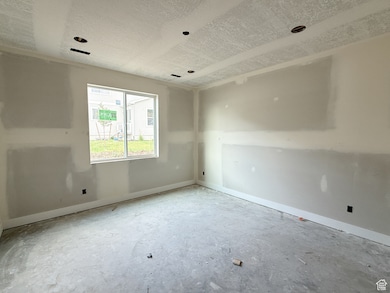 Empty room with a textured ceiling and baseboards