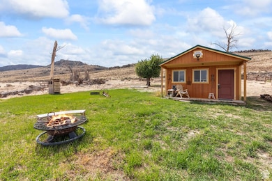 View of grassy yard with a fire pit, an outbuilding, and a mountain view