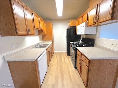 Kitchen featuring white appliances, a sink, light