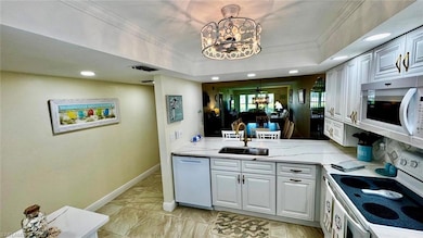 Kitchen featuring white appliances, a sink, a chandelier, baseboards, and ornamental molding