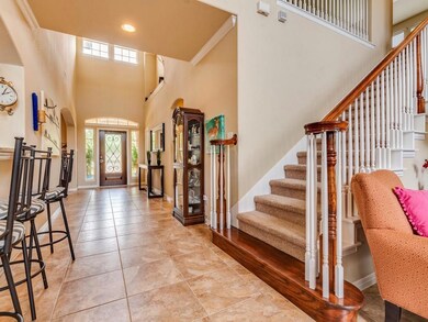 Entrance foyer featuring arched walkways, stairway, ornamental molding, a towering ceiling, and light tile patterned floors
