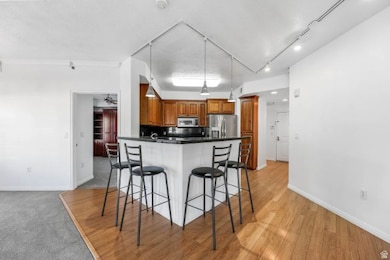 Kitchen with dark countertops, brown cabinetry, track lighting, a breakfast bar area, and stainless steel appliances