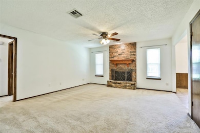 Unfurnished living room with a ceiling fan, a textured ceiling, light carpet, a fireplace, and baseboards