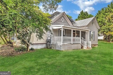 View of front of home with a porch, a front yard, and roof with shingles