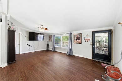 Entryway with ornamental molding, dark wood-type flooring, and a ceiling fan