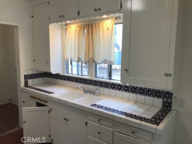 Kitchen with charming white cabinetry and custom tile work to go with the Spanish style architecture