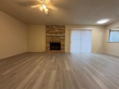 Unfurnished living room featuring a textured ceiling, a large fireplace, wood finished floors, and a ceiling fan