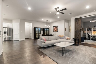 Living room with a barn door, a ceiling fan, rece