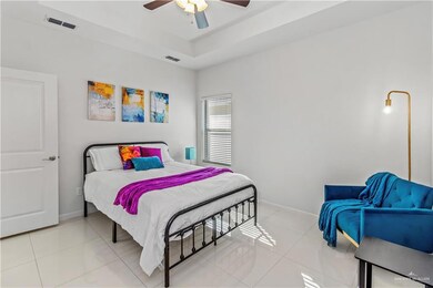 Tiled bedroom featuring a tray ceiling and ceiling fan