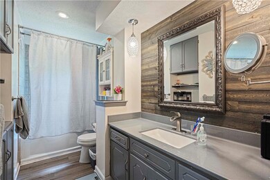 Full bathroom featuring a textured ceiling, wooden walls, hardwood / wood-style flooring, toilet, and vanity