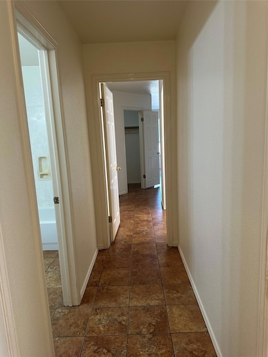 Hallway featuring baseboards and dark tile patterned floors