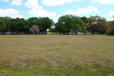 Wide view looking east from the street towards the 10th tee, with the practice facilities to the right of the lake.
