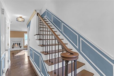 Staircase featuring crown molding, a fireplace, wood finished floors, a decorative wall, and a wainscoted wall