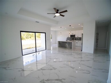 Unfurnished living room featuring a raised ceiling, light marble finish flooring, ceiling fan, and recessed lighting