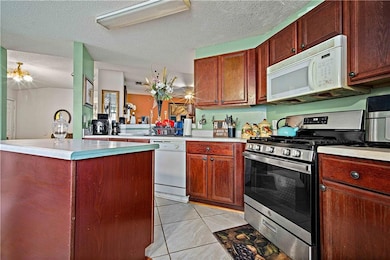 Kitchen with white appliances, light tile patterned floors, light countertops, a center island, and a textured ceiling