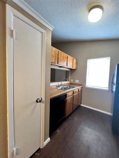 Kitchen featuring dishwashing machine, dark wood-