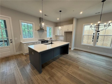 Kitchen with white cabinets, a sink, wall chimney 