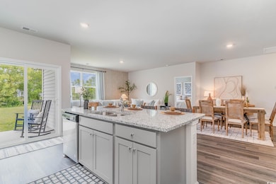 Kitchen with light stone countertops, an island with sink, dishwasher, recessed lighting, and dark wood-style flooring
